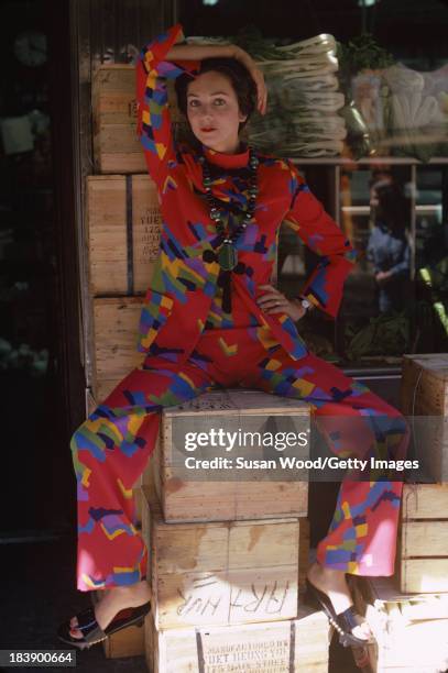 Portrait of an unidentified model dressed in a two-piece, print trouser suit and beaded cross necklace, Manhattan's Chinatown, New York, New York,...