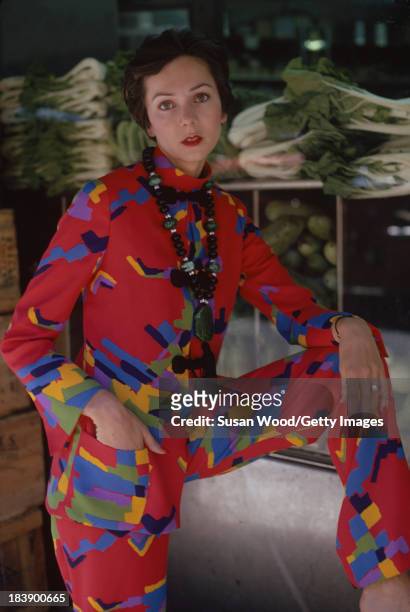 Portrait of an unidentified model dressed in a two-piece, print trouser suit and beaded cross necklace, Manhattan's Chinatown, New York, New York,...