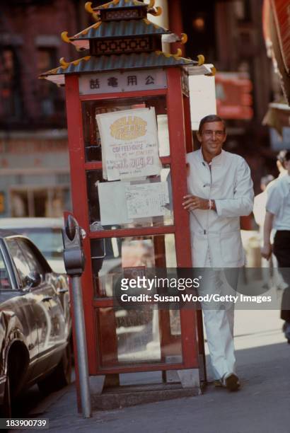 Portrait of German-born American fashion designer John Weitz dressed in one of his designs, a white suit with toggle fasterners, as he poses beside a...