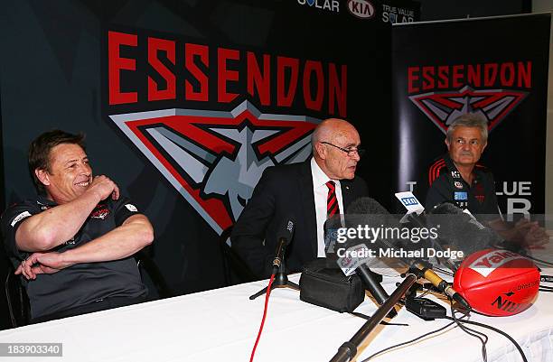 New Bombers coach Mark Thompson reacts next to Chairman Paul Little and new Senior assistant coach Neil Craig after dropping his mobile phone during...