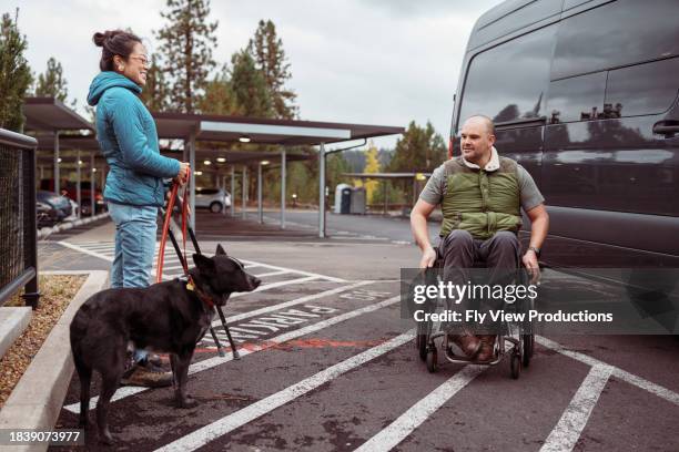 man using a wheelchair meeting a friend for lunch - service animal stock pictures, royalty-free photos & images