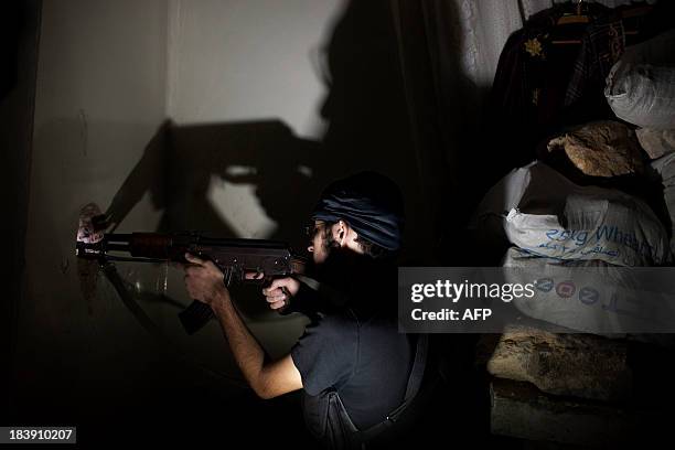 Opposition fighter Abu Yassin takes position inside a building in Salaheddin square, in Syria's northern city of Aleppo, on September 30, 2013....