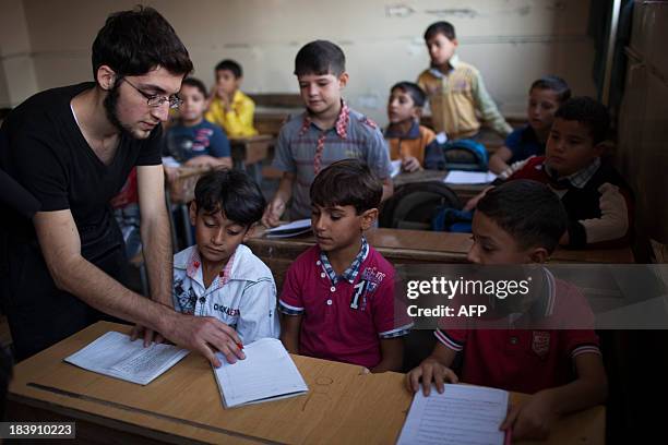 Opposition fighter Abu Yassin teaches a class to children in Saif Al-Dawla neighbourhood of Syria's northern city of Aleppo on September 30, 2013....