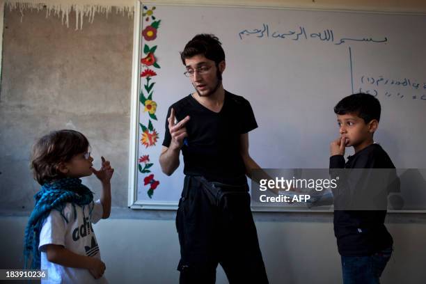 Opposition fighter Abu Yassin teaches a class to children in Saif Al-Dawla neighbourhood of Syria's northern city of Aleppo on September 30, 2013....