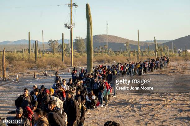 Immigrants line up at a remote U.S. Border Patrol processing center after crossing the U.S.-Mexico border on December 07, 2023 in Lukeville, Arizona....