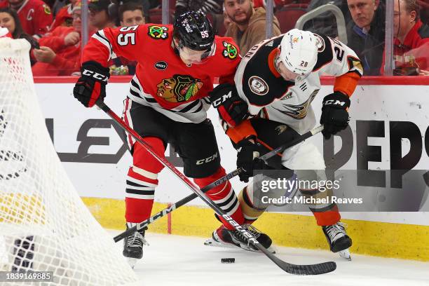 Kevin Korchinski of the Chicago Blackhawks and Brett Leason of the Anaheim Ducks battle for control of the puck during the third period at the United...