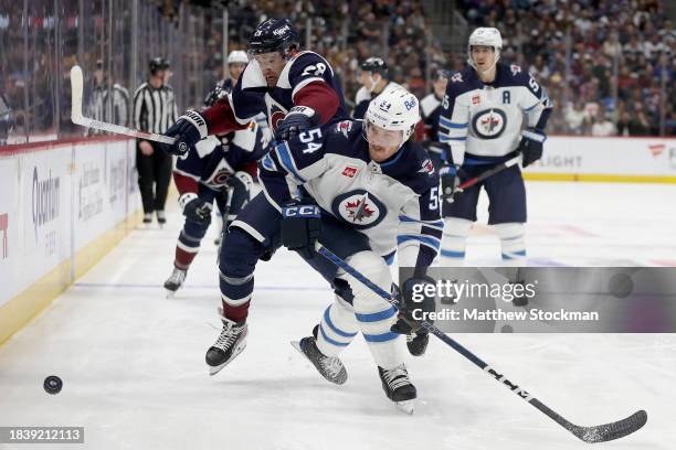 Miles Wood of the Colorado Avalanche fights for the puck against Dylan Samberg of the Winnipeg Jets in the second period at Ball Arena on December...