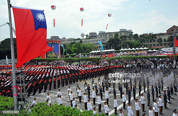 Members of a Taiwanese military band and people wearing hats in the colours of Taiwan's national flag take part in celebrations to mark National Day...