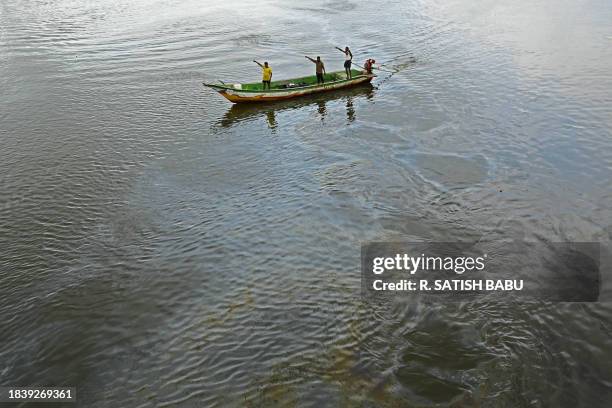 Fishermen sail in a boat through the oil spilled over the backwater at Ennore creek in the aftermath of Cyclone Michaung, on the outskirts of Chennai...