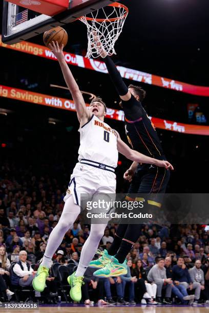 Christian Braun of the Denver Nuggets attempts a layup over Jusuf Nurkic of the Phoenix Suns during the first half at Footprint Center on December...
