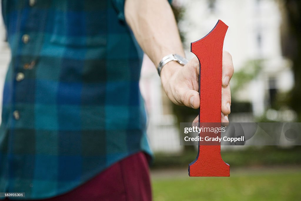 Young man holding 'one' model figure