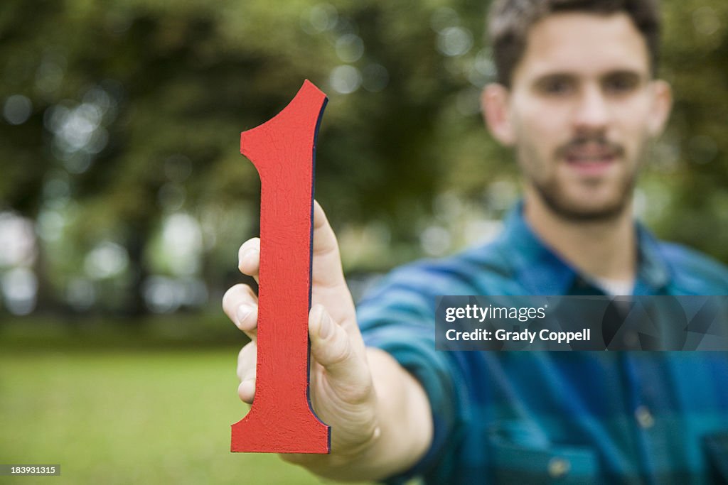 Young man holding  'one' model figure