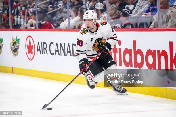 Tyler Johnson of the Chicago Blackhawks plays the puck around the boards during first period action against the Winnipeg Jets at the Canada Life...