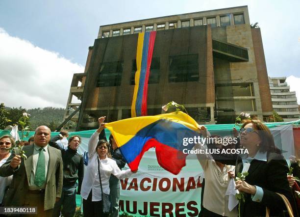 Demonstrators raise flowers 10 February in front of the El Nogal nightclub in Bogota. The protesters denounced terrorism three days after a car bomb...