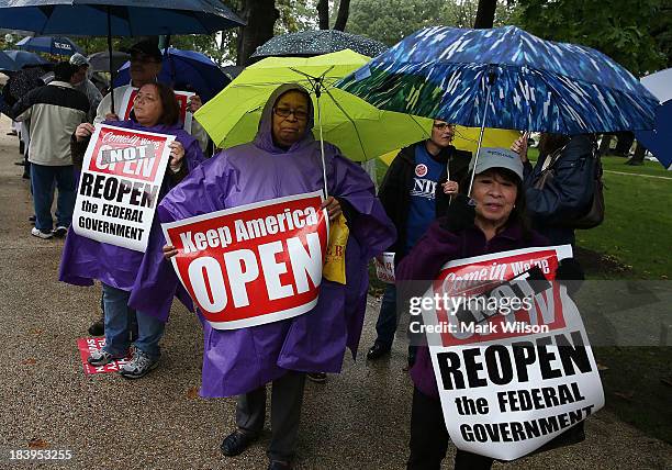 People hold signs during a rally to urge Congress to end the government shutdown at the U.S. Capitol, October 9, 2013 in Washington, DC. The U.S....