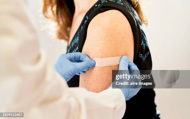 doctor applying band-aid to his patients after receiving the third dose of vaccine for immunization - vaccination stock pictures, royalty-free photos & images