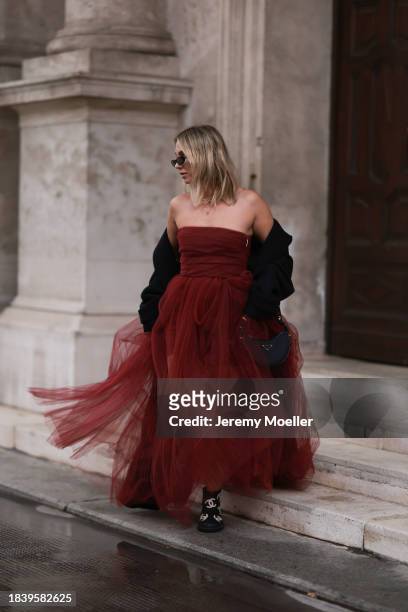 Karin Teigl seen wearing Saint Laurent brown tortoise sunglasses, H&M Studio red ruffled tulle long bandeau dress, gold necklaces, H&M black wool...