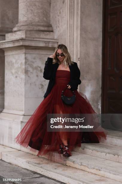 Karin Teigl seen wearing Saint Laurent brown tortoise sunglasses, H&M Studio red ruffled tulle long bandeau dress, gold necklaces, H&M black wool...