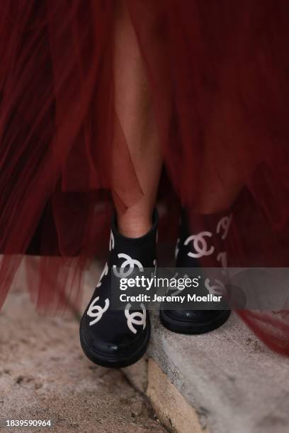 Karin Teigl seen wearing H&M Studio red ruffled tulle long bandeau dress and Chanel black logo rubber boots, on November 25, 2023 in Vienna, Austria.