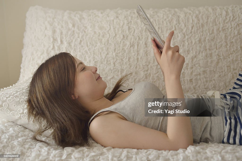 Women using digital tablet on the sofa.