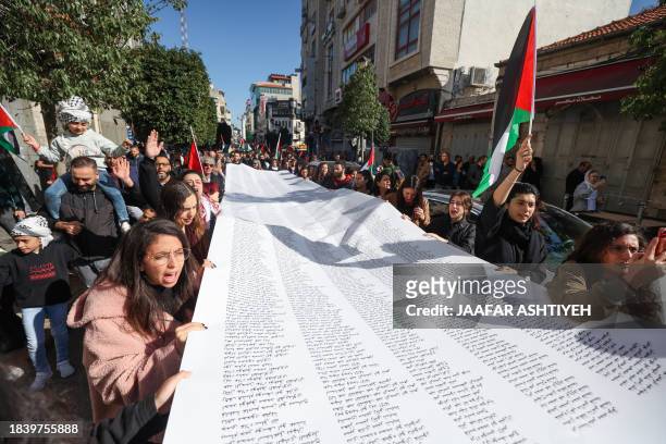 Palestinians carry a list of Gaza victims during a rally amid a general strike in Ramallah city in the occupied West Bank on December 11 in...