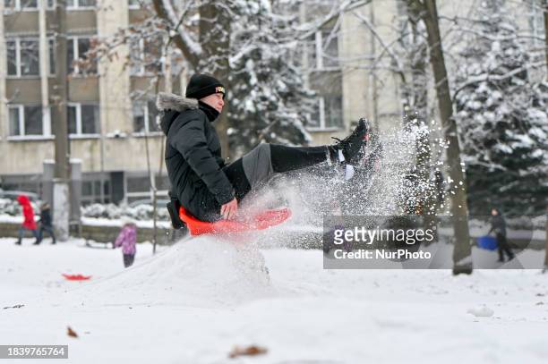 Boy is jumping on a bump in a plastic sledge in Lviv, Ukraine, on December 10, 2023.
