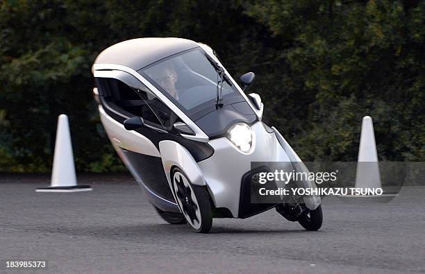 This photo taken on October 10, 2013 shows a journalist driving Japanese auto giant Toyota Motor's prototype model electric trike "i-Road", in Tokyo....