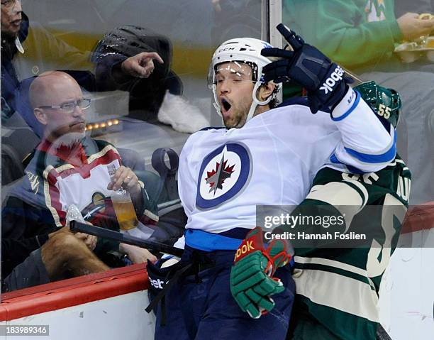 Mathew Dumba of the Minnesota Wild checks Eric Tangradi of the Winnipeg Jets into the boards during the first period of the game on October 10, 2013...