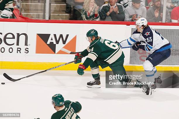 Mikael Granlund of the Minnesota Wild skates with the puck as Mark Scheifele of the Winnipeg Jets defends during the game on October 10, 2013 at the...
