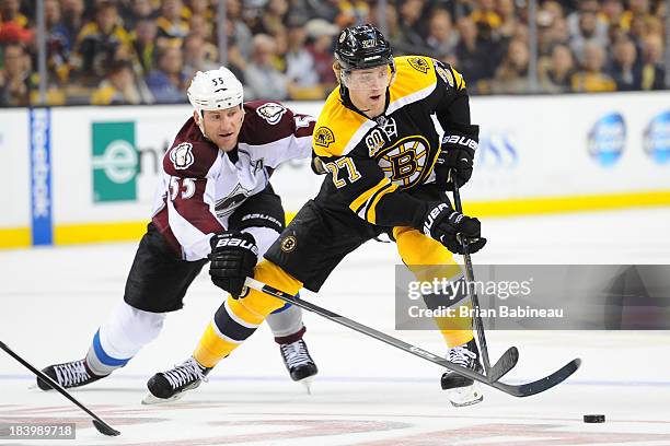 Dougie Hamilton of the Boston Bruins skates with the puck against Cody McLeod of the Colorado Avalanche at the TD Garden on October 10, 2013 in...