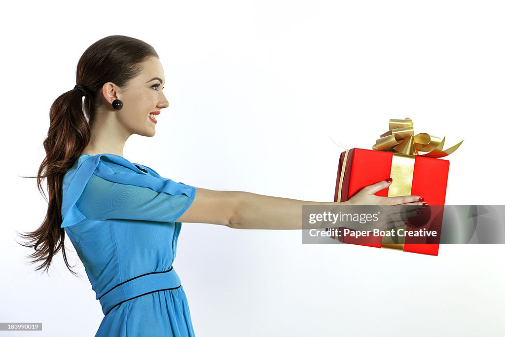 Lady offering a big red gift with a gold ribbon