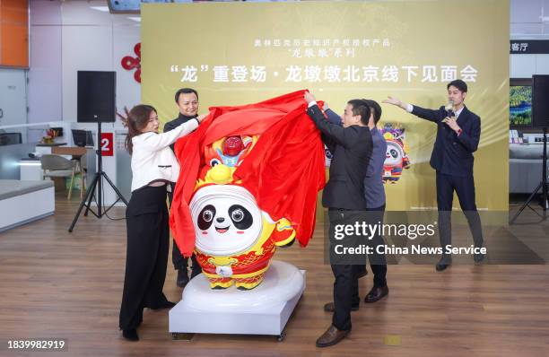People unveil a Chinese zodiac Dragon version of Bing Dwen Dwen, a Beijing Winter Olympic Games mascot, during an offline activity at a store on...