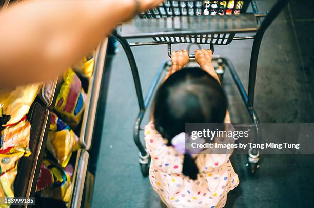 toddler help pushing shopping cart in supermarket - supermarket help stock-fotos und bilder