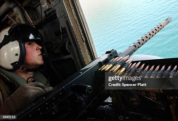 Marine keeps watch out of a helicopter before landing on the USS Bataan flight deck March 10, 2003 in the Persian Gulf. The Bataan, a multi-purpose...