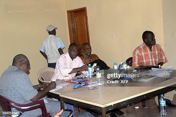 Unidentified people sit around the Commission of centralisation of results of the commune of Matoto in Conakry on October 10, 2013. Twelve days after...