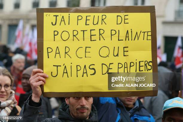 Protestor holds a placard reading "I'm afraid to file a complaint because I don't have any documents" during a demonstration called by associations...