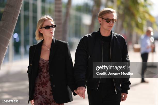 Ave Rohtla seen wearing black sunglasses, black oversized blazer jacket, red flower print pattern midi dress, Jacquemus Bambino Long black leather...