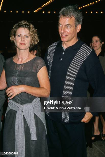 American actress Pam Dawber, wearing a dark grey dress with a light grey sweater tied around her waist, and her husband, American actor Mark Harmon,...