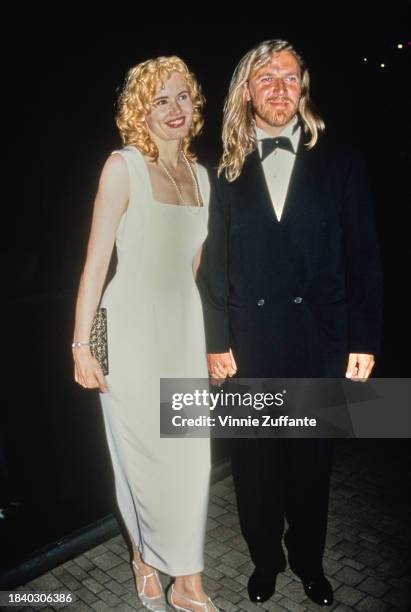 American actress Geena Davis, wearing a white evening gown, and Finnish film director Renny Harlin, who wears a tuxedo and bow tie, attend the...