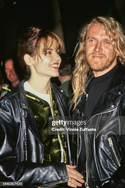 American actress Geena Davis, wearing a black leather jacket over a green velvet outfit and a white crew neck top, and her husband Finnish film...