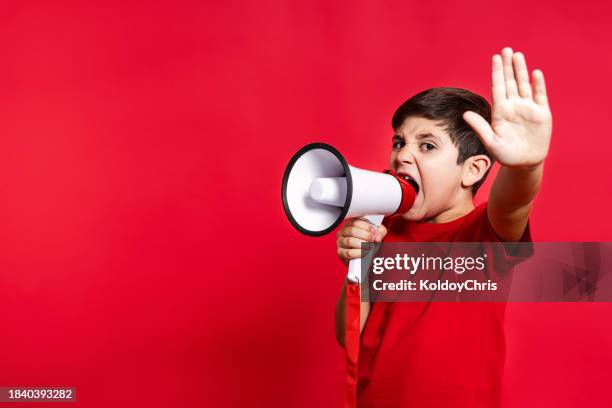 boy in red shouting into megaphone with stop gesture - stopschild stock-fotos und bilder