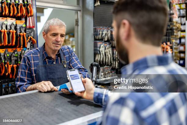 man making a contactless payment at a hardware store - digital wallet stock pictures, royalty-free photos & images
