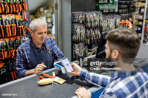 cliente che effettua un pagamento contactless presso un negozio di ferramenta - ferramenta foto e immagini stock