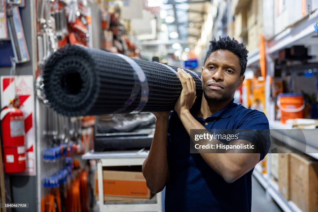 Atendente de varejo que trabalha em uma loja de ferragens carregando uma malha de arame