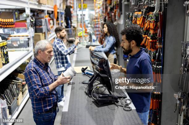 man shopping at the hardware store and talking to the retail clerk - bouwmarkt stockfoto's en -beelden