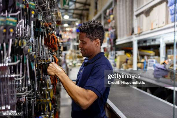 happy salesman working at a hardware store and searching for a wrench - shop assistant stock pictures, royalty-free photos & images