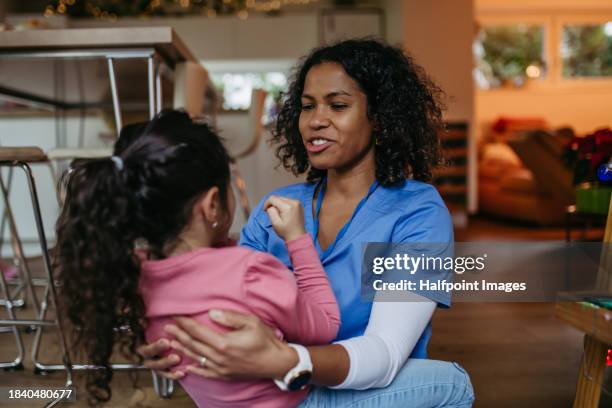 nurse, doctor returning home to her little daughter, arriving home and giving hug to girl. lifestyle of healthcare worker as parent. - sitting on ground stock pictures, royalty-free photos & images