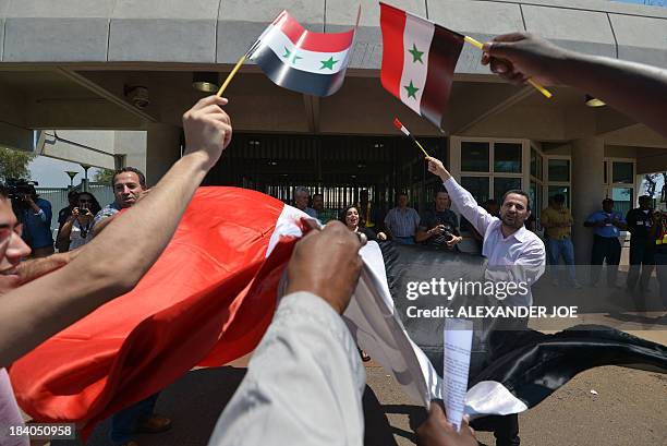 Syrians and members of the Congress of South African Trade Unions wave Syrian flags outside the US embassy in Pretoria on October 11, 2013 during a...