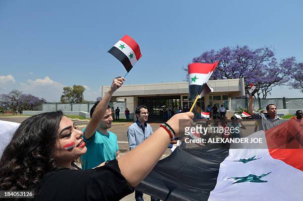 Syrians and members of the Congress of South African Trade Unions wave Syrian flags outside the US embassy in Pretoria on October 11, 2013 during a...