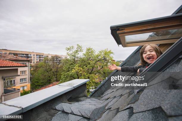smiling child looking through the attic window - hand uitsteken stockfoto's en -beelden